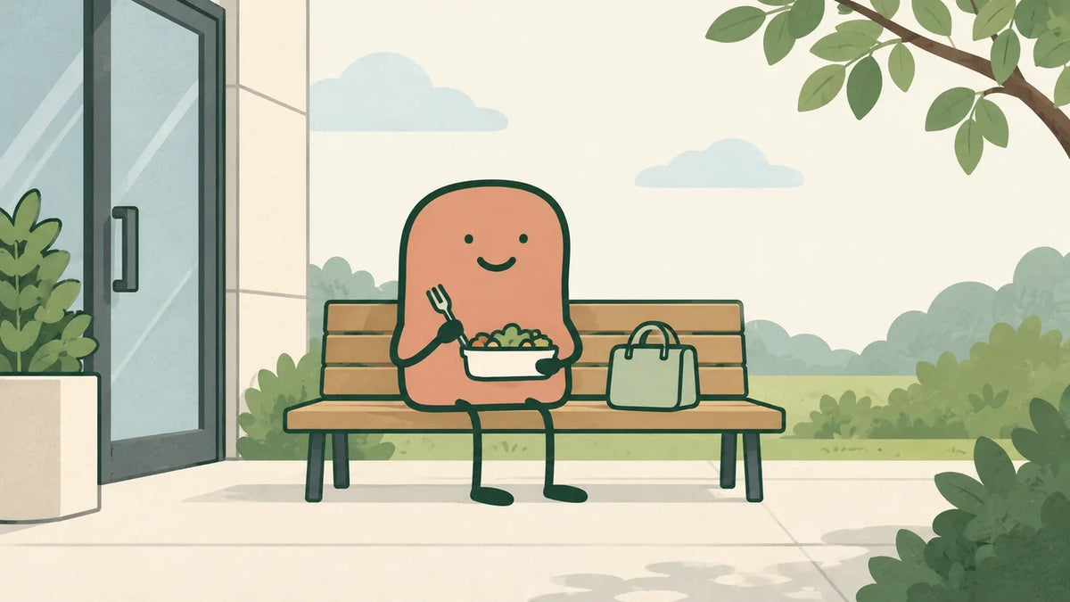A terracotta companion eats lunch on an outdoor bench beside an office entrance and a green bag.
