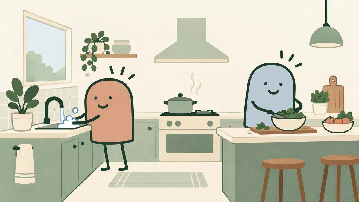 Terracotta character washing hands at a sink while a blue companion prepares food on a separate clear counter in a shared kitchen.