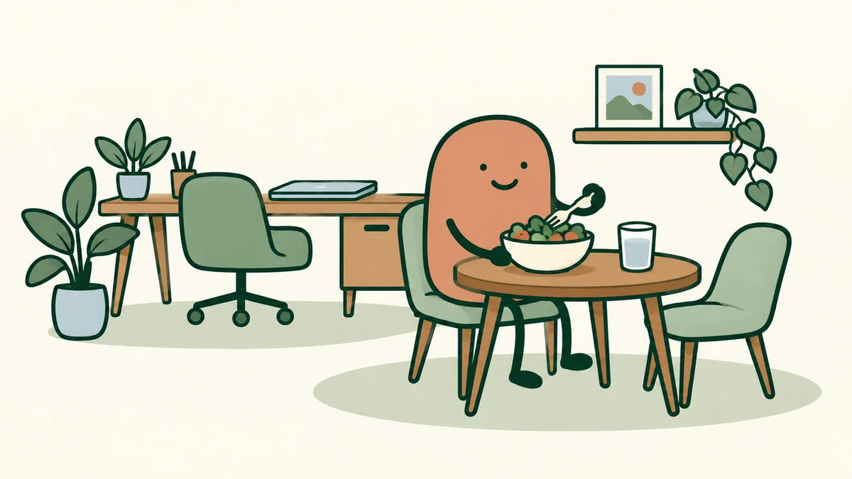 A worker eats lunch at a separate table, with a closed laptop on the desk behind.
